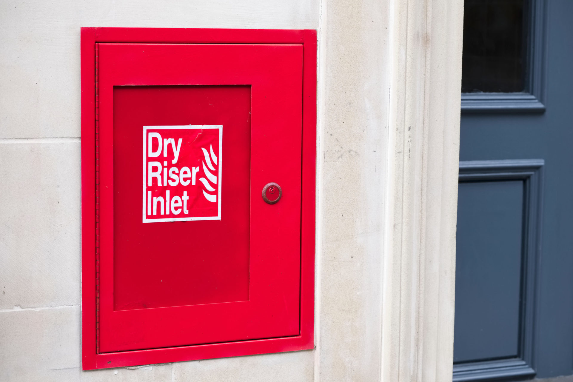 Dry riser red inlet box and sign at wall